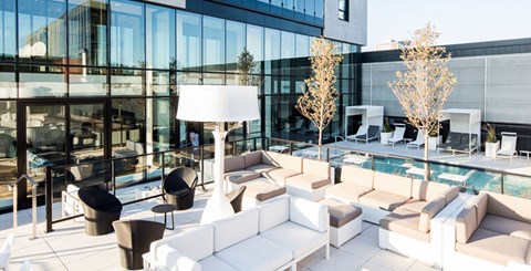 A modern outdoor seating area with white furniture and a pool.