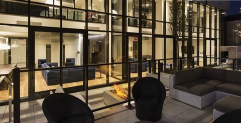 A modern living room with black furniture and glass walls.