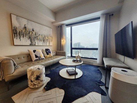 A modern living room with a large painting on the wall and a view of the city.