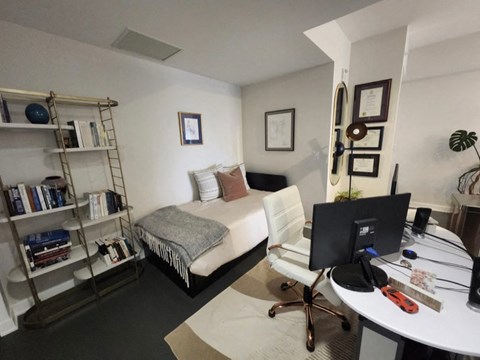 A room with a bed, desk, and bookshelf.