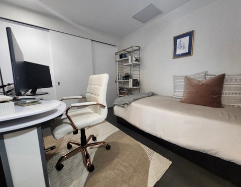 A white chair is in front of a desk with a computer monitor on it.