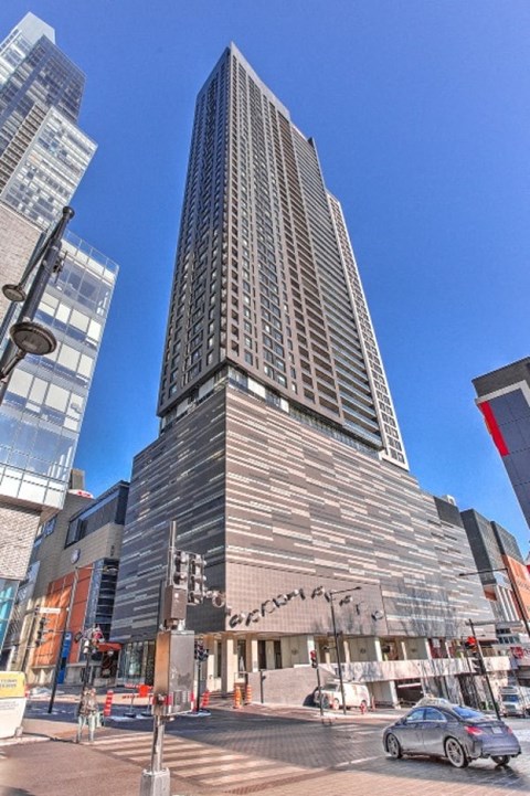 A tall building with a curved facade stands in front of a clear blue sky.