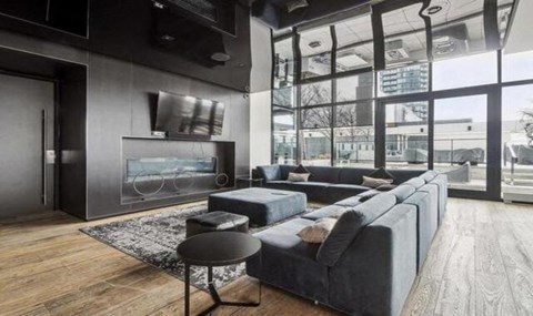 A modern living room with a grey sofa and a black stool.