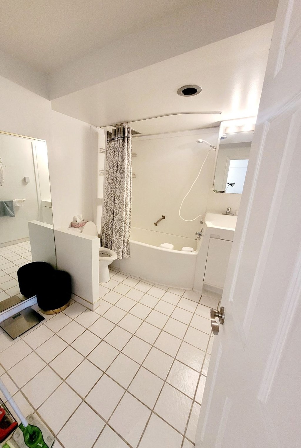 A bathroom with a white tile floor and a white door.