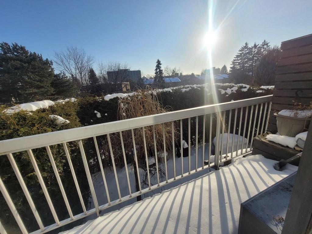 A sunny day on a balcony with snow on the ground.