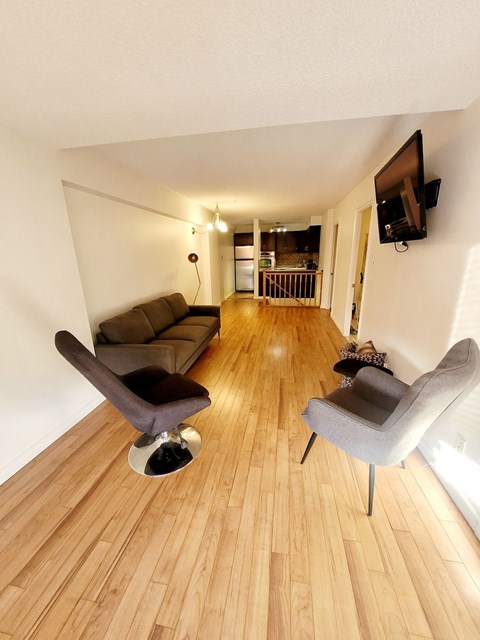 A living room with a couch, chair and television.