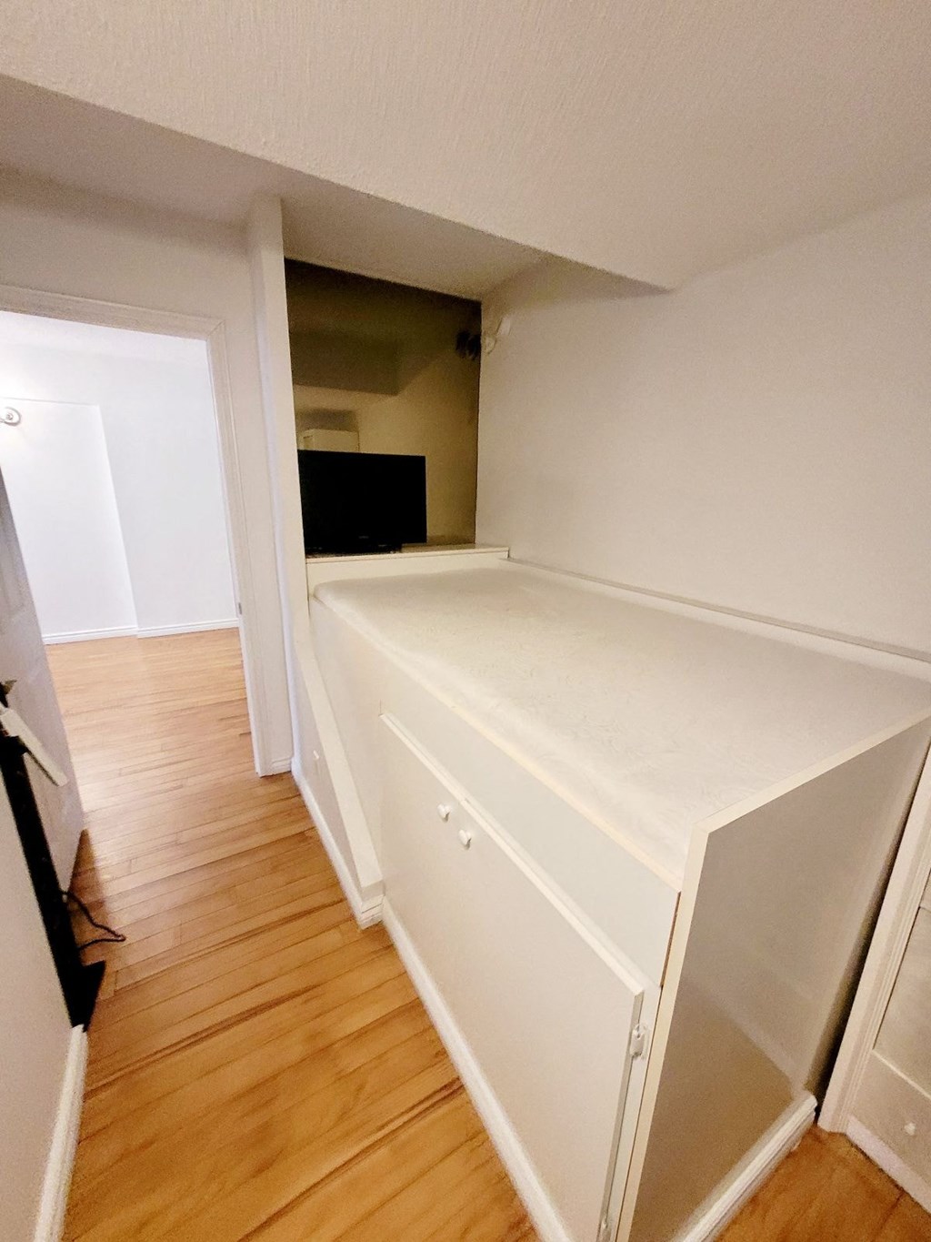 A white kitchen with a wooden floor and a white cabinet.
