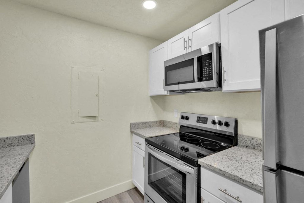 A kitchen with a stove, microwave, and refrigerator.