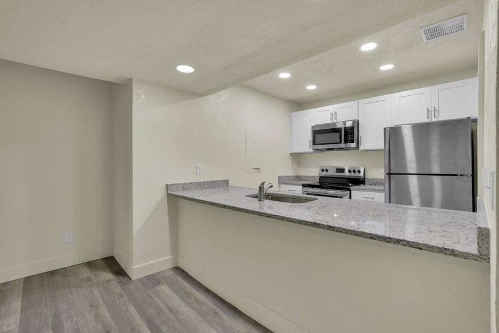 A kitchen with a stainless steel refrigerator and microwave above the counter.