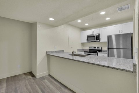A kitchen with a stainless steel refrigerator and microwave above the counter.