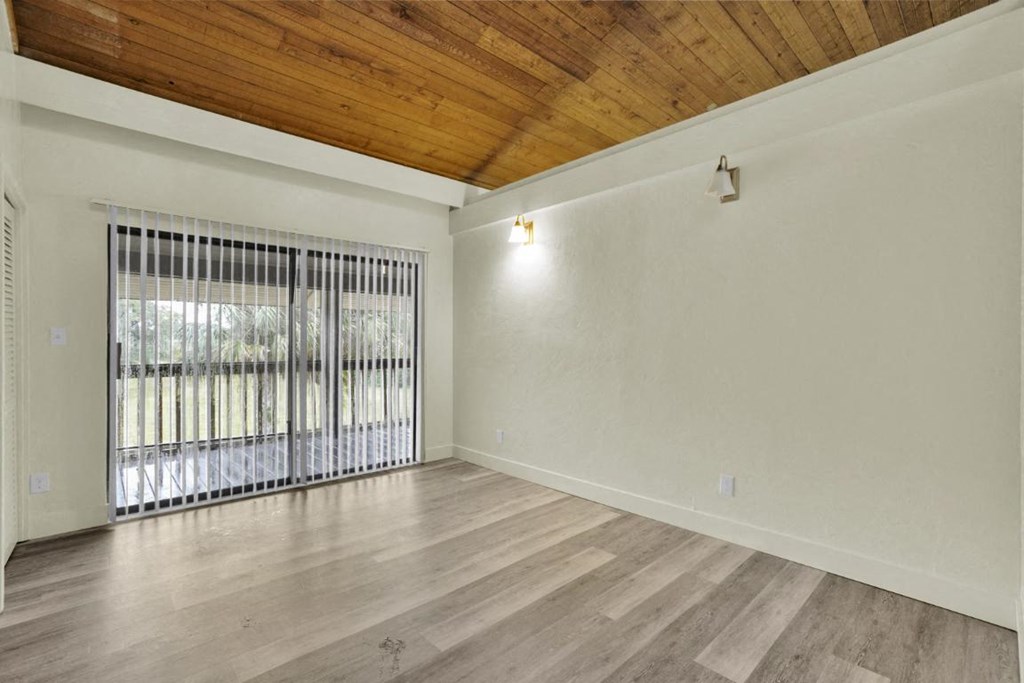 A room with a wooden ceiling and a window with a metal grate.