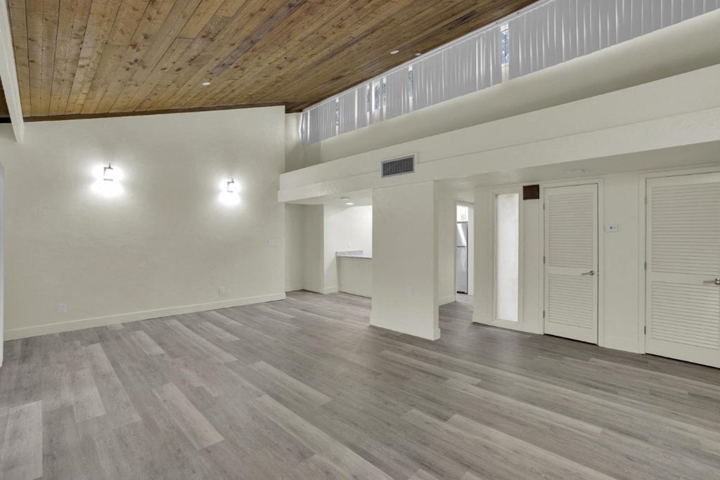 A spacious room with wooden floors and white walls.