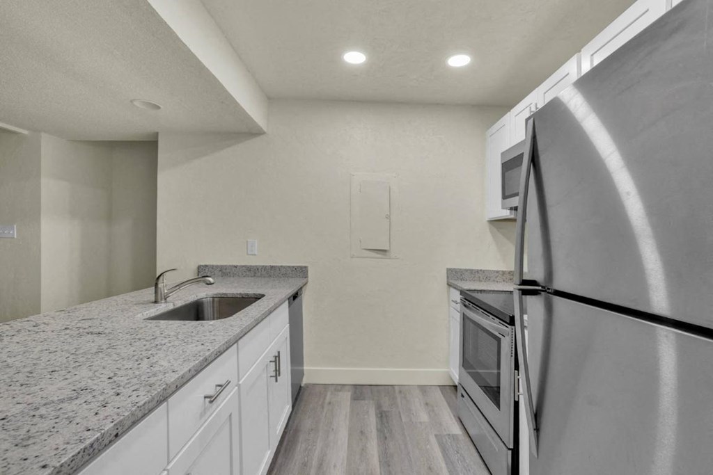 A kitchen with a granite countertop and stainless steel appliances.