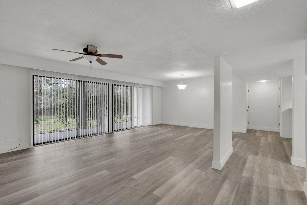 A room with a ceiling fan and sliding glass doors.