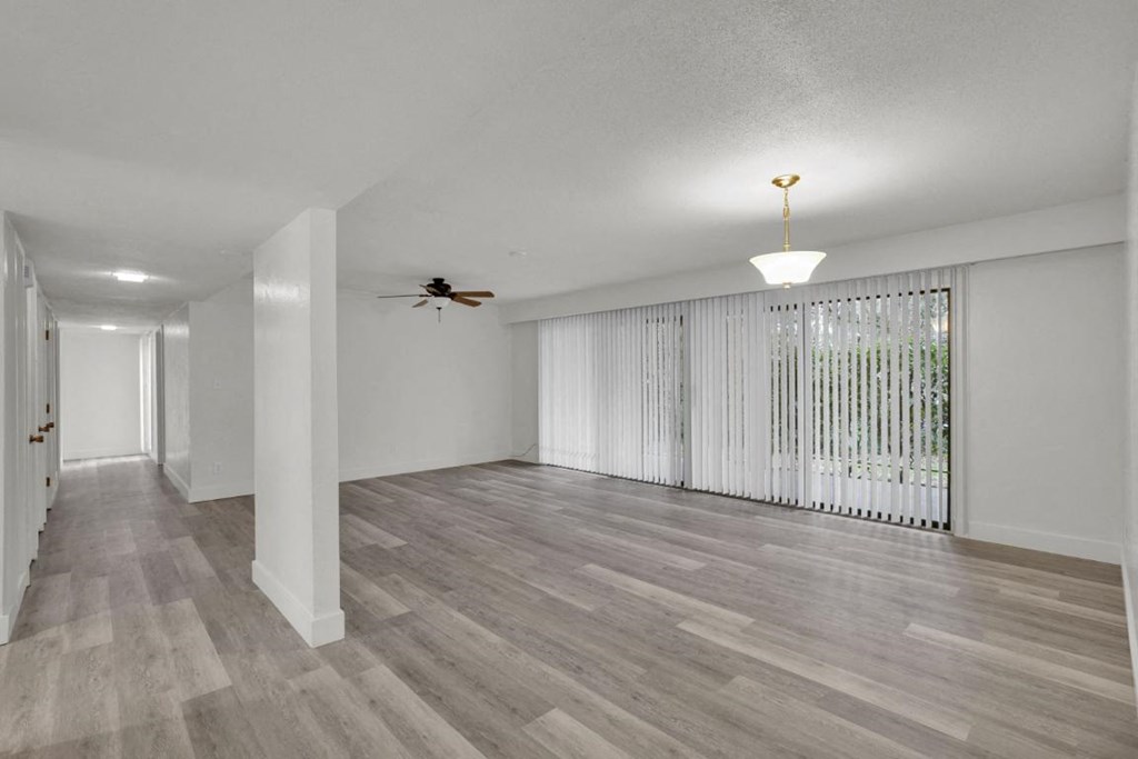 A room with a ceiling fan and a window with white curtains.