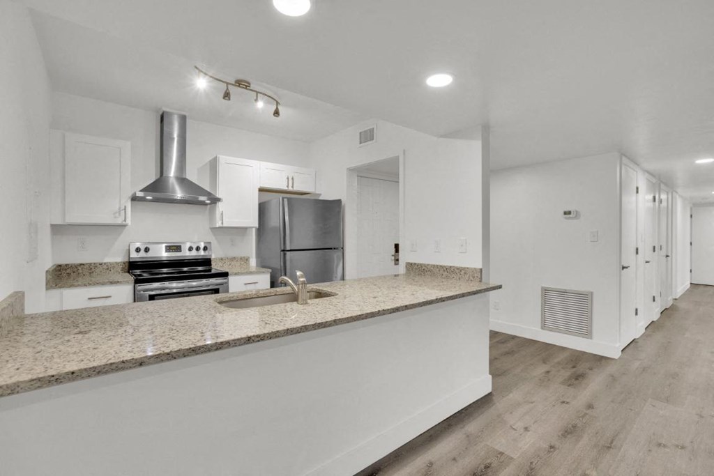 A kitchen with a stove, sink, and refrigerator.