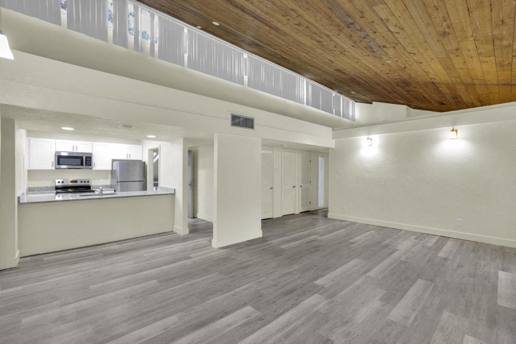 A spacious room with wooden ceiling and grey flooring.