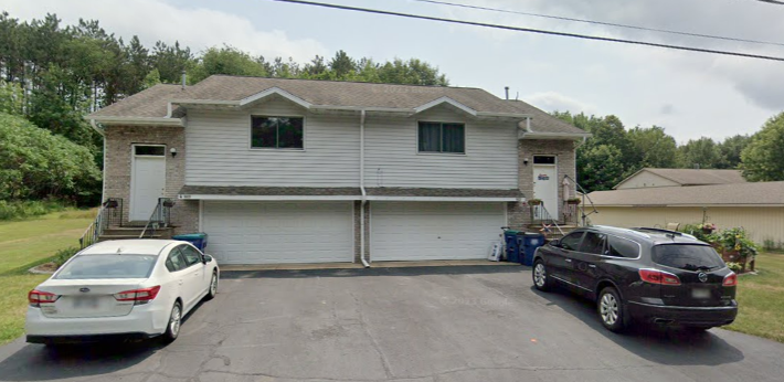 A two-story house with a garage and a car parked in front.