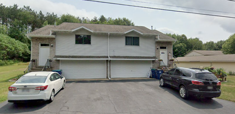 A two-story house with a garage and a car parked in front.
