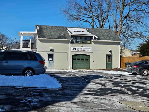 A grey van is parked in front of a building with a green door.