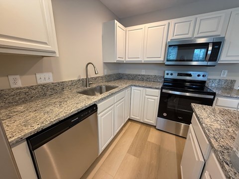A kitchen with white cabinets and granite countertops.
