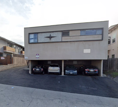 A carport with four cars parked in it.