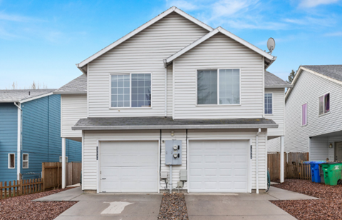 A two-story house with a garage and a satellite dish on the roof.