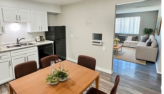 A kitchen with a table and chairs in the foreground and a couch in the background.