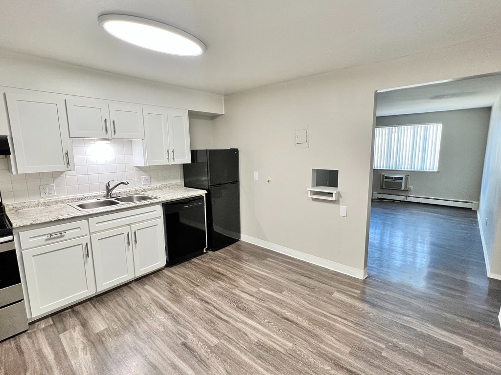 A kitchen with white cabinets and a black fridge.