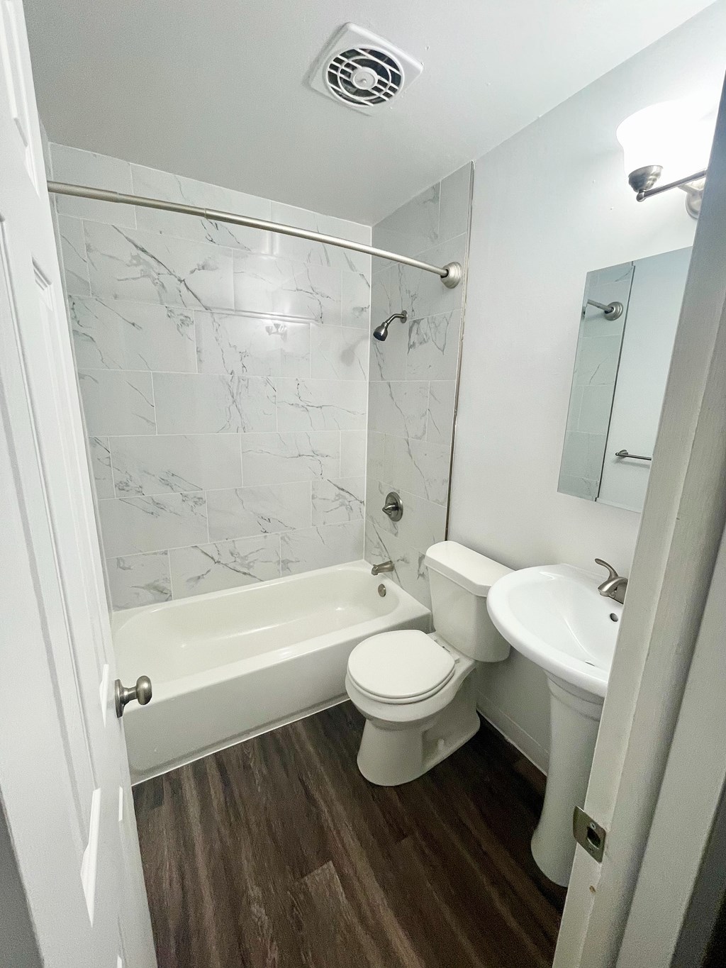 A white bathroom with a marble tile wall.