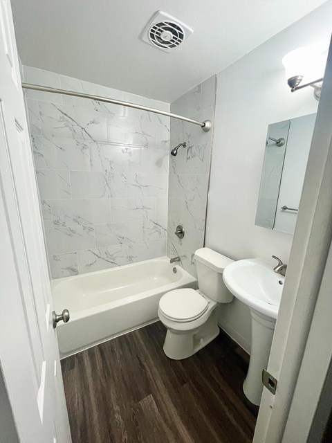 A white bathroom with a marble tile wall.