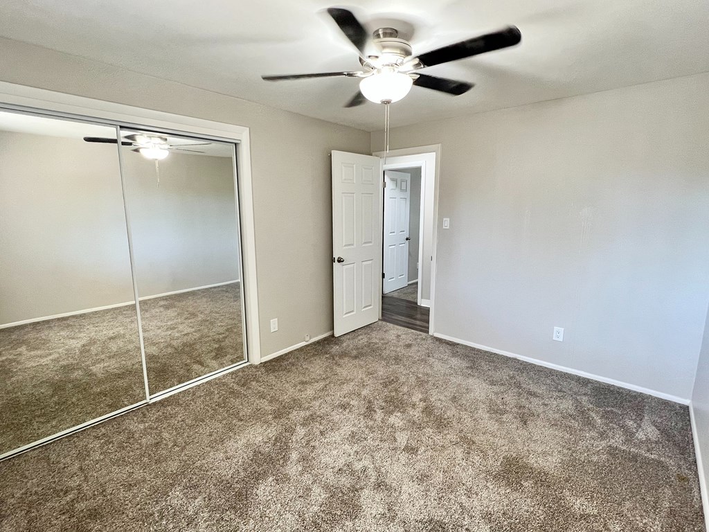 A room with a ceiling fan and a carpeted floor.