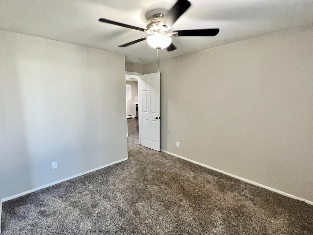 A room with a ceiling fan and carpeted floor.
