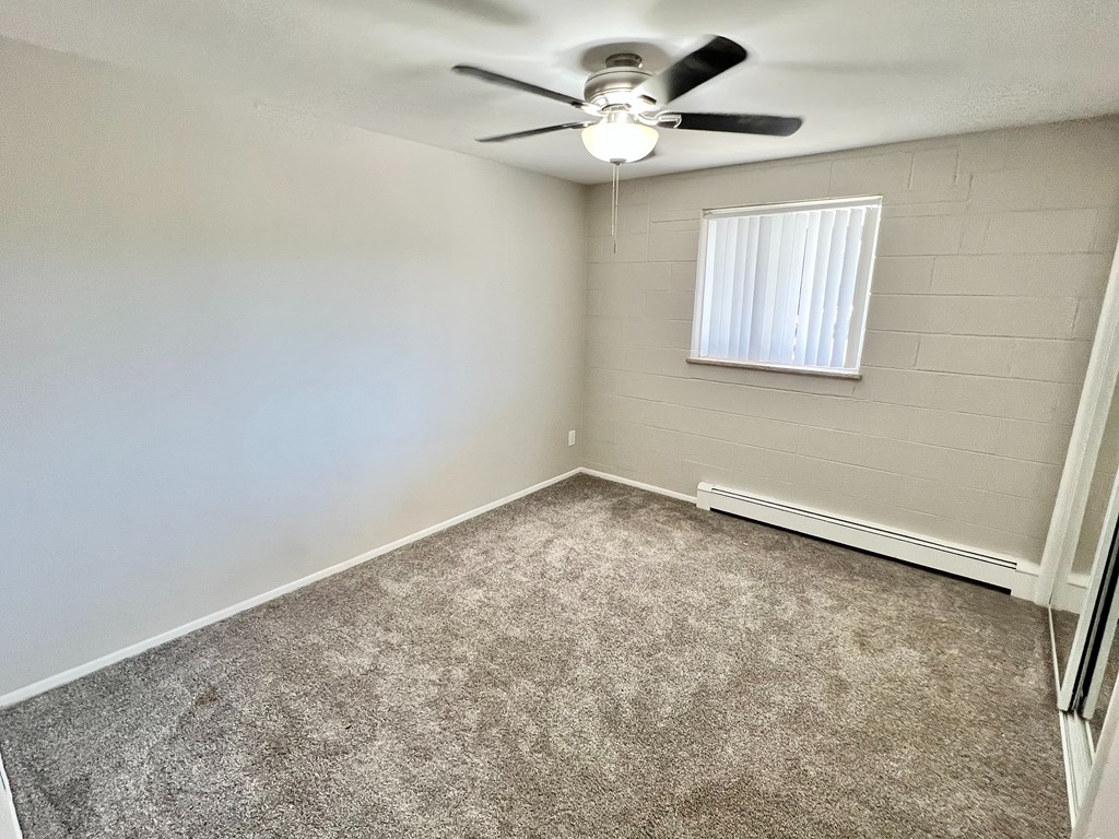 A room with a ceiling fan and carpeted floor.