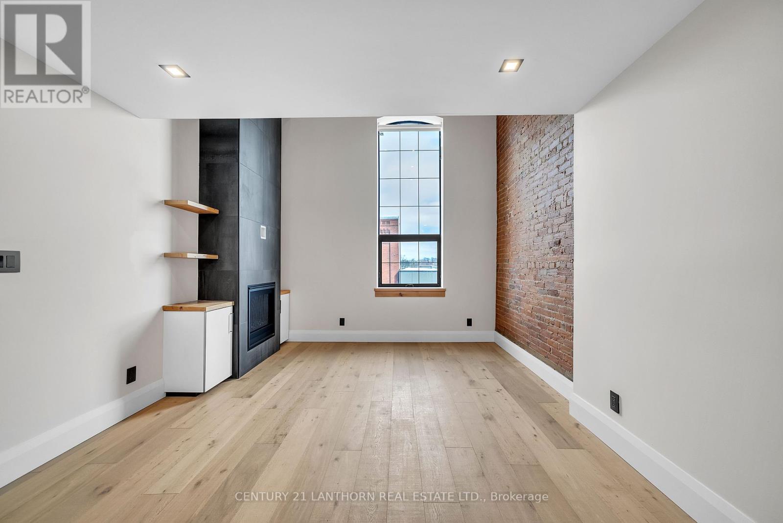 A spacious room with wooden floors and a brick wall.