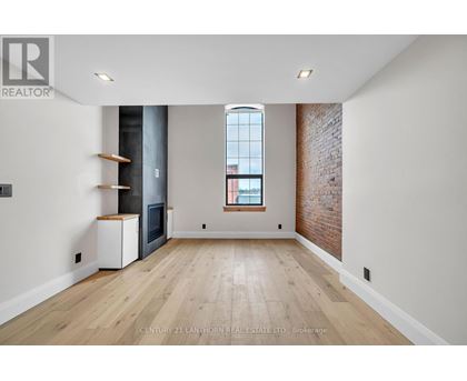 A spacious room with wooden floors and a brick wall.