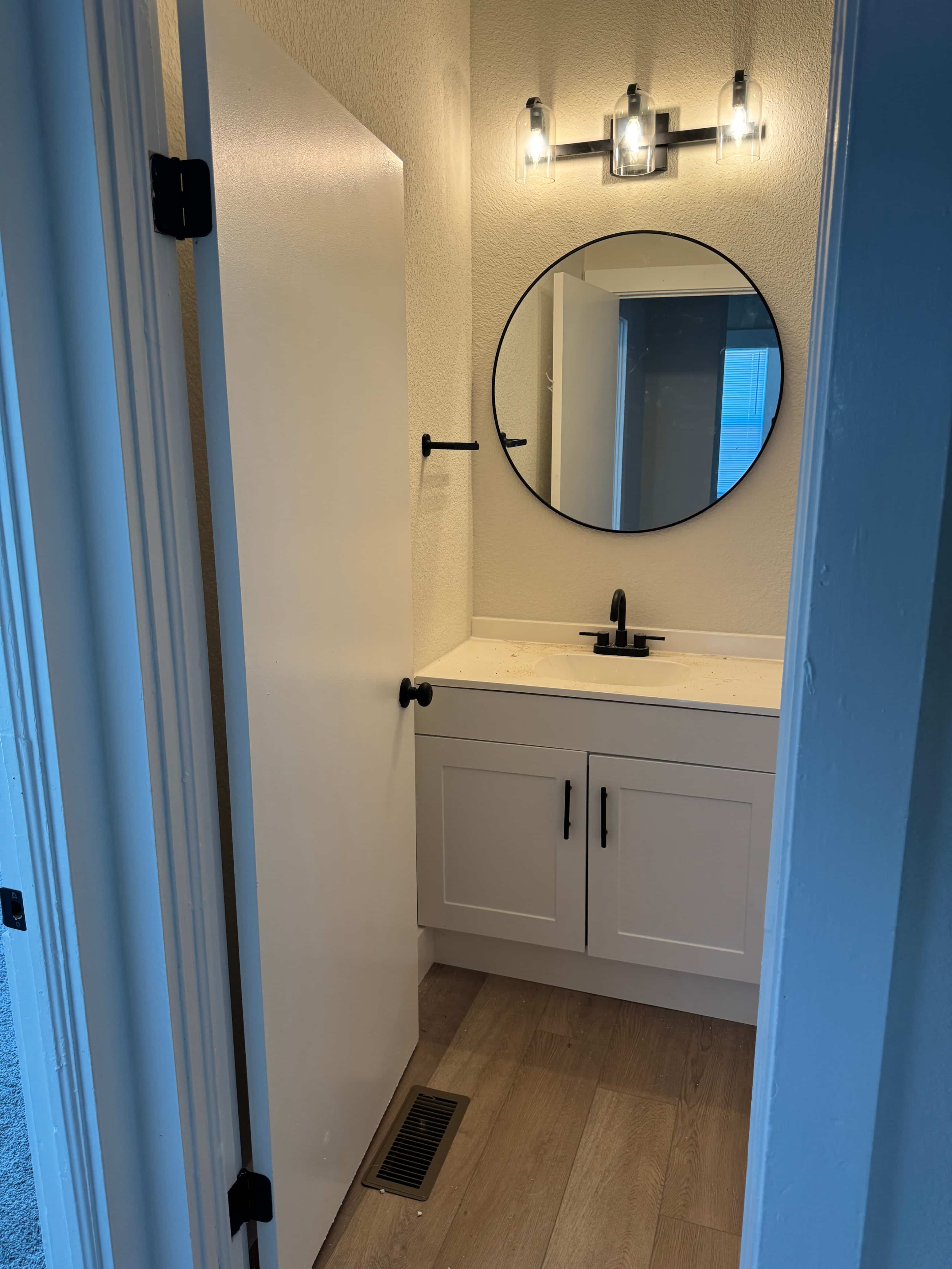 A bathroom with a round mirror and a sink.
