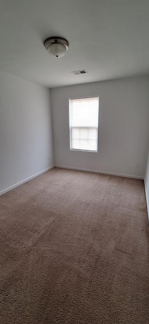 A room with a carpeted floor and a window.