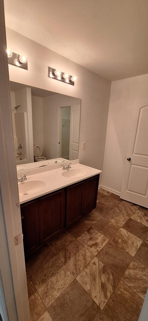 A bathroom with a white sink and brown tiled floor.