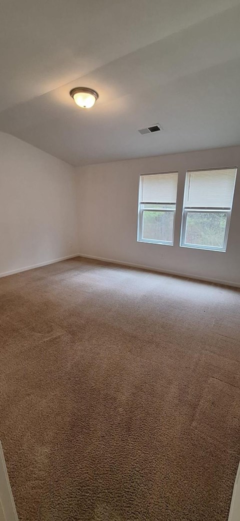 A room with a brown carpet and a window.