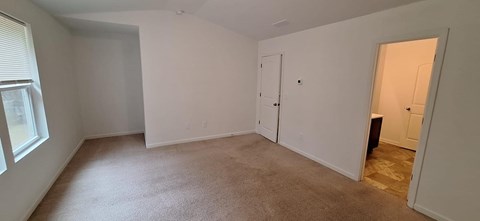 A large empty room with carpeted floor and white walls.