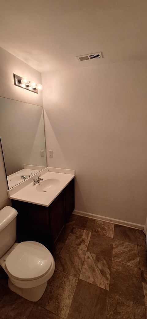 A bathroom with a toilet, sink, and mirror.