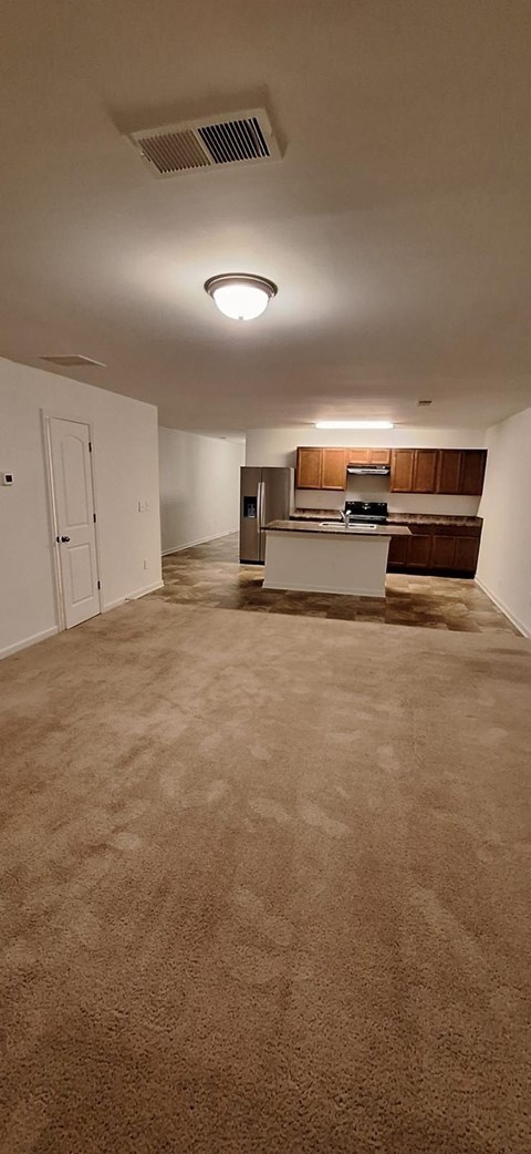 A room with a carpeted floor and a ceiling fan.