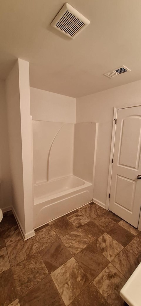 A bathroom with a tiled floor and a white door.