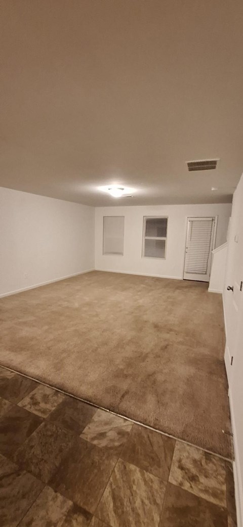 A room with a brown carpet and a white wall.