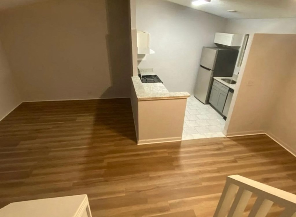A kitchen area with a refrigerator, sink, and countertop.