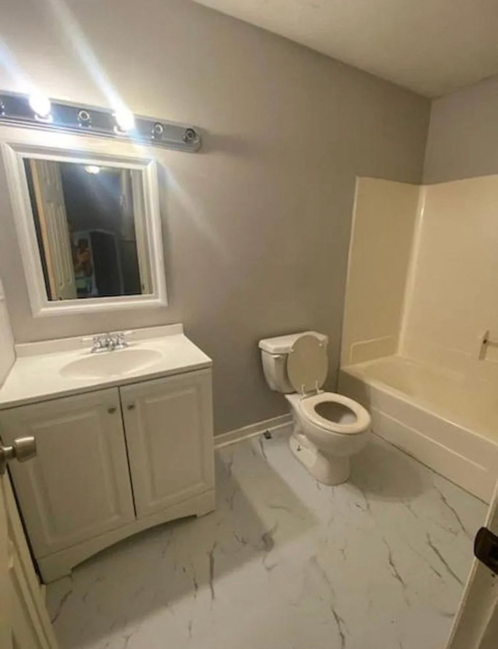 A bathroom with a toilet, sink, and mirror.
