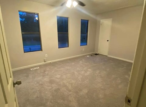 A room with a carpeted floor and a ceiling fan.