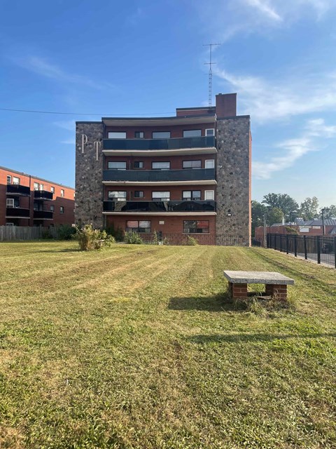 A grassy field with a bench and a building in the background.