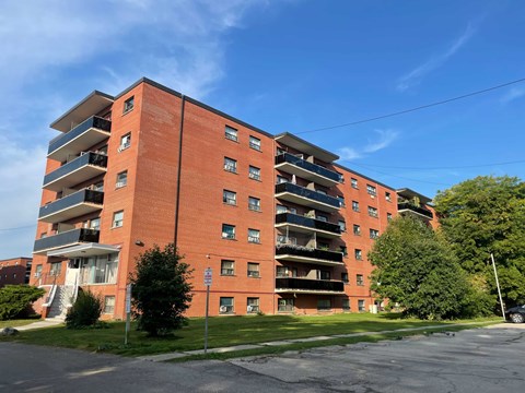 A red brick apartment building with a clear blue sky in the background.
